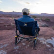 Man in a navy topo Firepit Rocker watching sunset on a rocky overlook.
